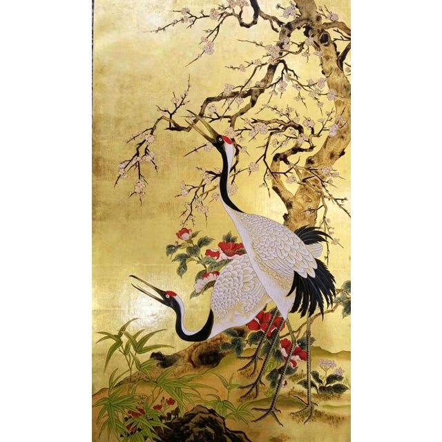 A luxurious hand painted gold leaf wallpaper featuring an elegant oriental scene of graceful cranes, blooming plum...