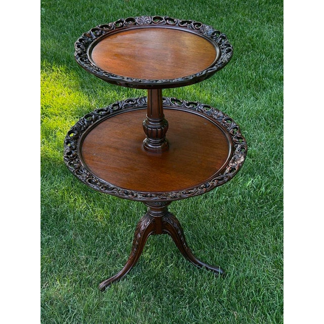 Such a stunning, two-tiered, carved, mahogany table—perfect for displaying desserts, collectibles, books, or plants! It...
