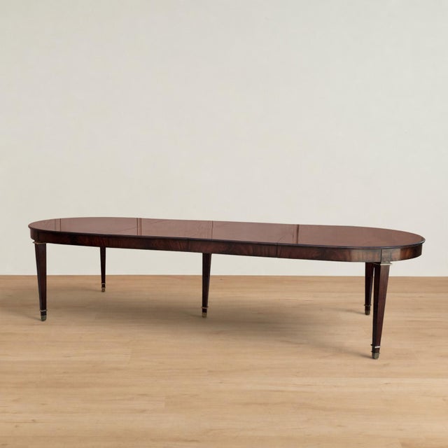 Impressive Louis XVI style dining table featuring an elegant oval ended top veneered in richly figured flame mahogany,...