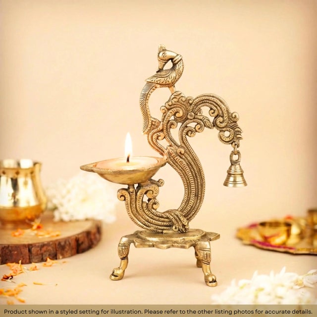 Illuminate your home with the divine glow of our Antique Gold Brass Peacock Diya with Hanging Bell. This masterfully...