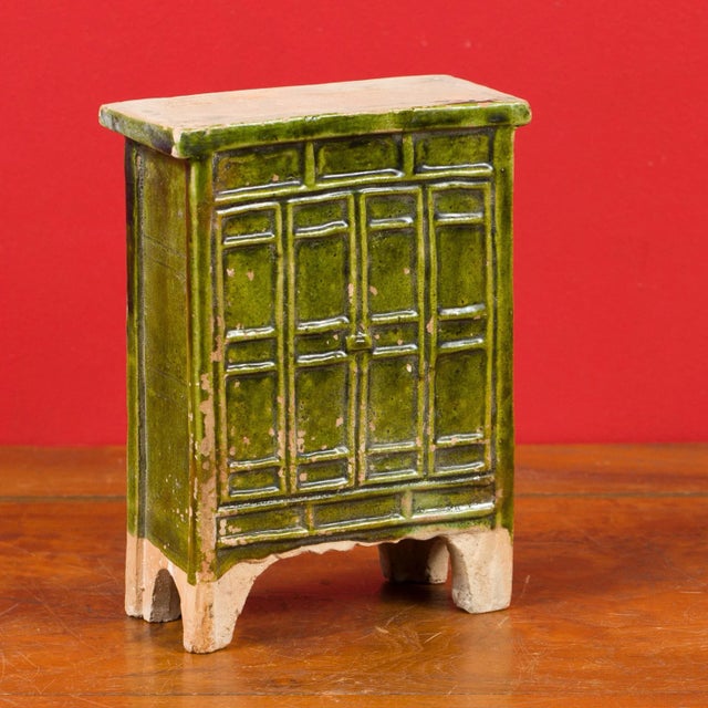 A Chinese Ming Dynasty period miniature terracotta armoire with green glazed finish and bracket feet. Created in China...