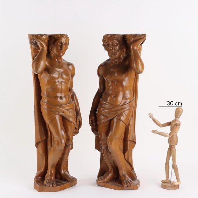 Pair of carved wooden sculptures depicting male figures. This piece is attributed to the mentioned designer/maker. It has...