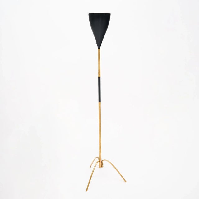 Floor lamp in the mid-century style from Italy. This fixture has a brass structure with a conical shade of Black lacquered...