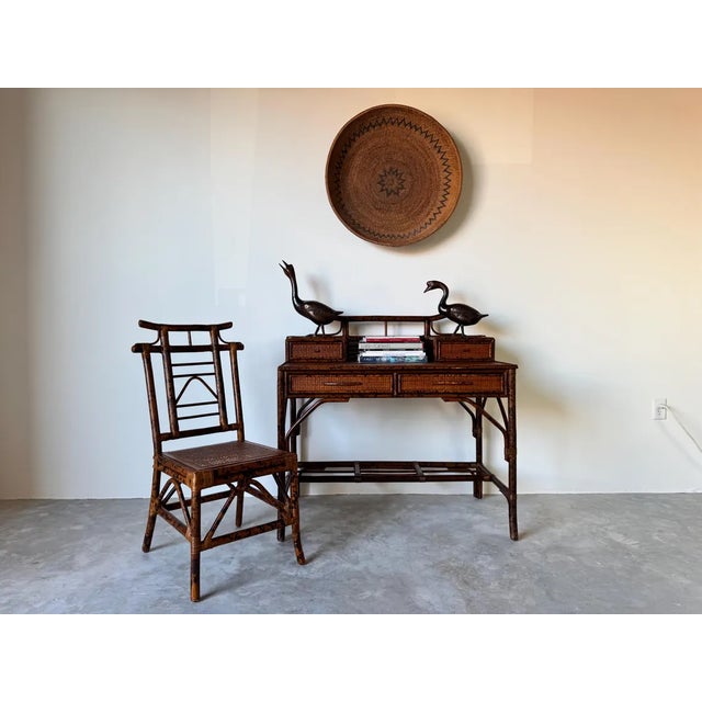 This stunning vintage British Colonial-style desk and chair set exudes timeless elegance with its faux burnt bamboo frame...
