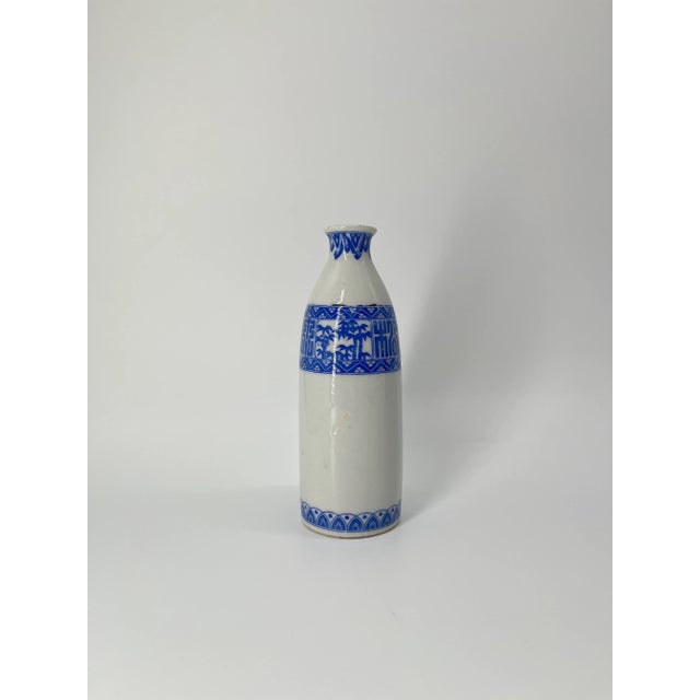 A beautiful vintage Japanese sake bottle (tokkuri) featuring an elegant blue floral motif around the body and neck. The...