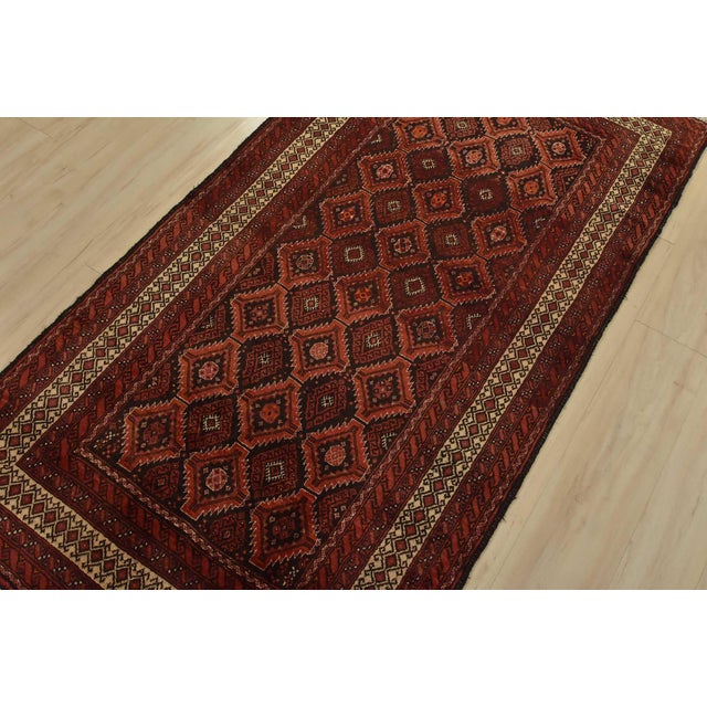 An authentic vintage tribal Baloch rug hand-knotted with fine wool and natural dyes. This nomadic rug features a geometric...