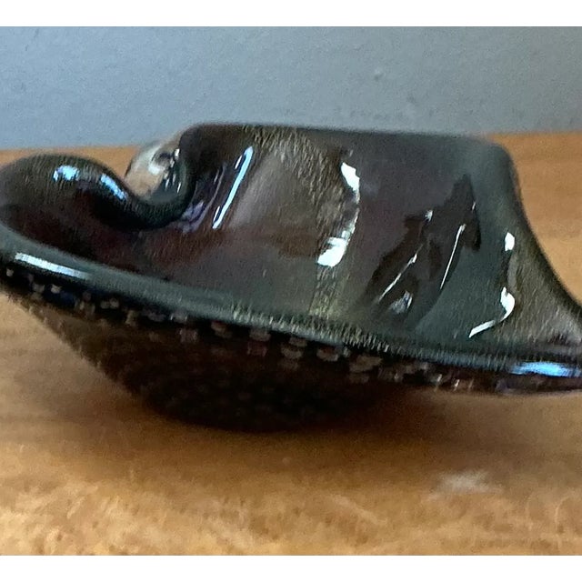 This vintage Italian Murano glass bowl brings sculptural movement and hand-blown character to a compact decorative form....