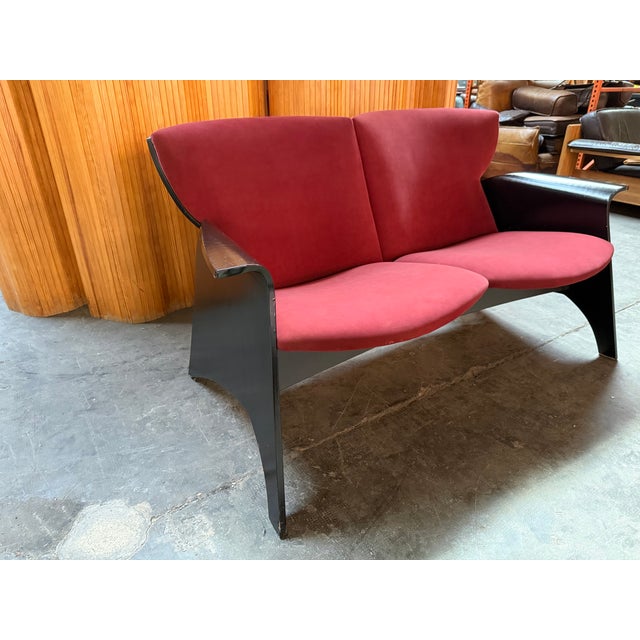 Conspicuous 80s black sofa with burgundy velvet upholstery.