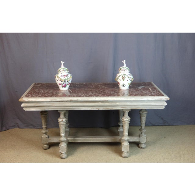 A painted wooden center table with a marble top. This table rests on six legs joined by a stretcher. Late 19th century....