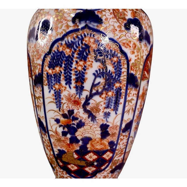 This is a classic tall Imari vase that dates to the Meiji period. It is beautifully decorated with a wisteria reserve to...