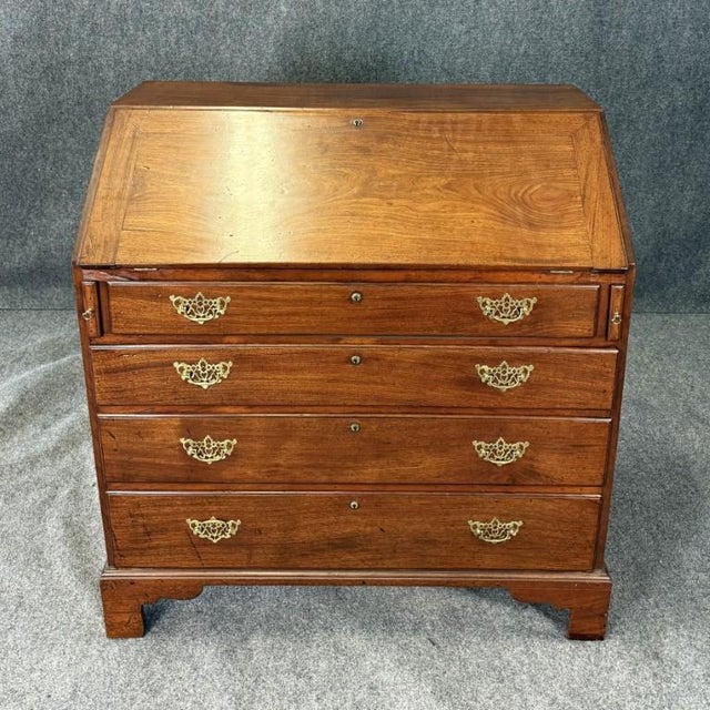 This 18th century mahogany secretary desk features a slant-front fall opening to a fitted interior with small drawers and...