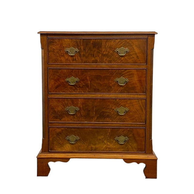 Vintage four drawer chest featuring a richly figured veneer across the drawer fronts, creating a pronounced grain pattern...