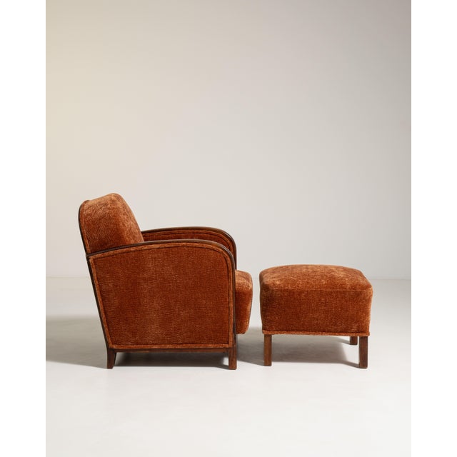 A classic Art Deco lounge chair paired with an ottoman, reflecting the period’s focus on comfort and geometric elegance....