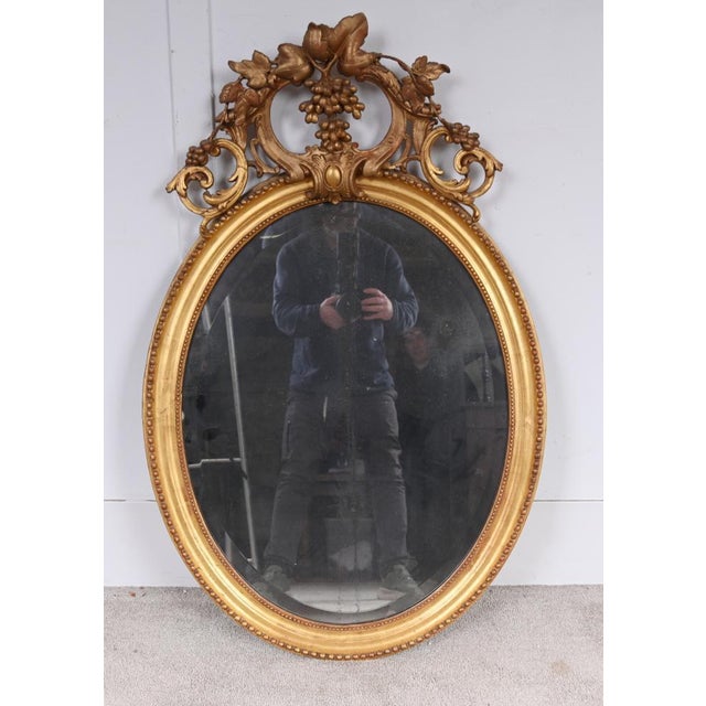 Fine Regency style giltwood oval mirror, with elegant beaded surround and a beautifully carved crest centred by trailing...
