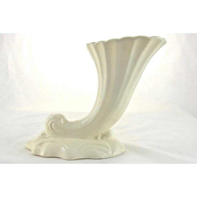 Ivory cornucopia vase with a fluted body, scalloped rim, and wave-like base. Marked “Made In Japan.” Light wear.
