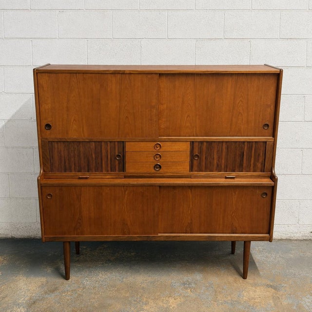 A substantial Danish teak highboard designed by Johannes Andersen, combining generous storage with a thoughtfully...