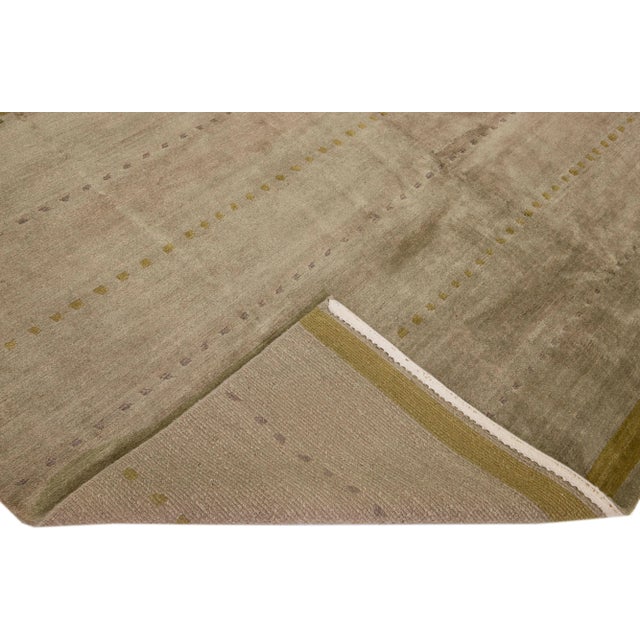 Beautiful modern Tibetan hand-knotted wool and silk rug with a gray and taupe color field. This Tibetan rug has a green...