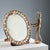 Table mirror with beaded frame, gems, and clear and pink glass flowers. Wooden frame. This piece is attributed to the...