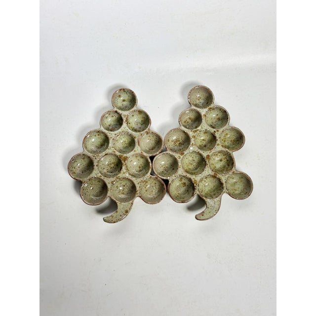 A pair of French snail or egg holders dating from the 1980s, made of glazed ceramic. Each piece has a stylized cluster...