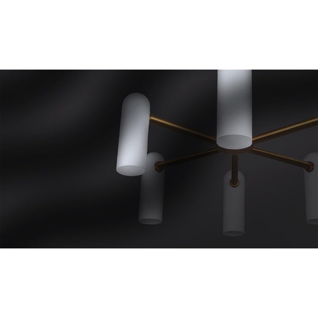 Offered by Schwung Spokes of brass hold slender lampshades, the circle of light creating a planetary effect in this...
