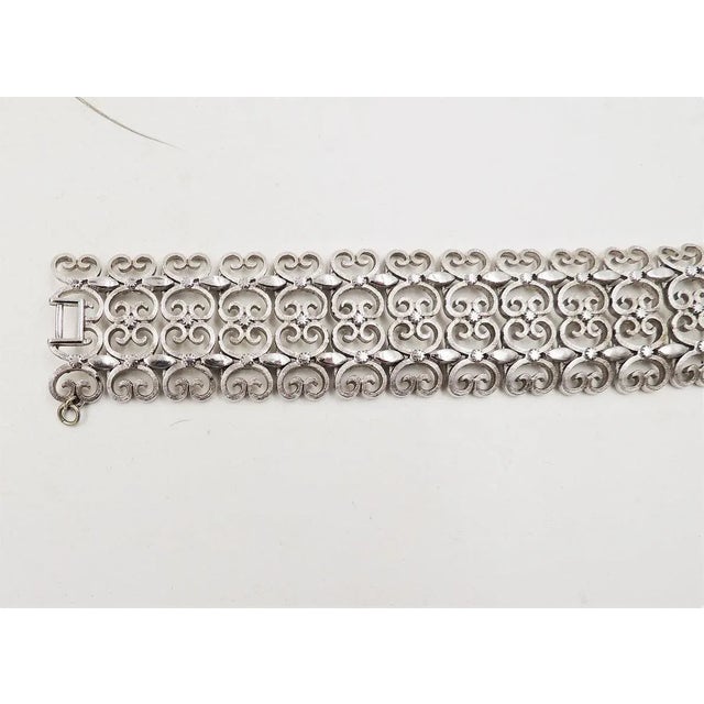 This is part of Chairish’s Costume Jewelry assortment. Rhodium plated filigree open work bracelet with fold over clasp and...