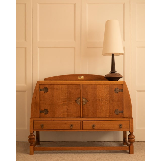 English work - 1930s a storage unit in solid light oak with a flared side, opening to reveal two doors and two drawers....