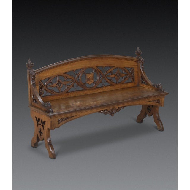 A large c19th oak hall bench, with arched back with pierced carving featuring intertwined trifold and quatrefoils, flanked...
