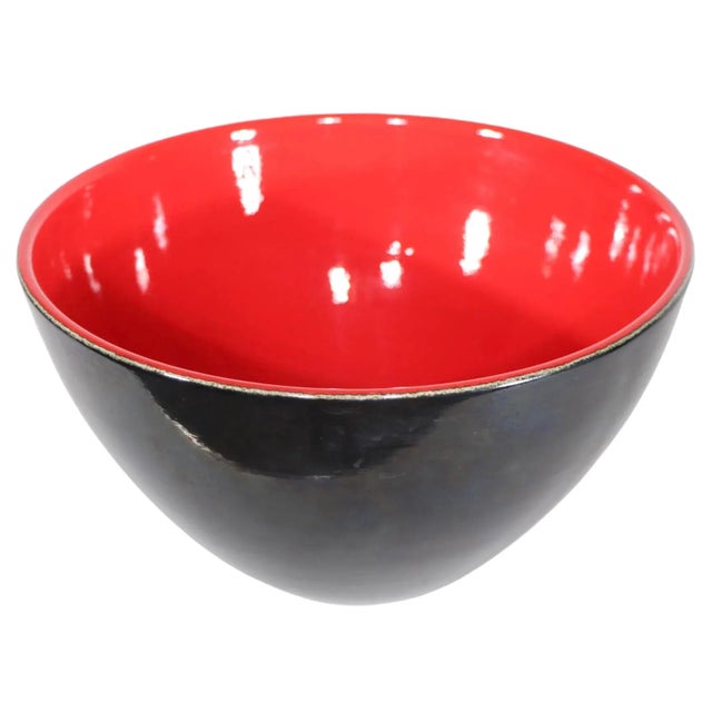Stunning ceramic bowl having a black exterior, red interior, and subtle white line between the two dominant colors, at the...
