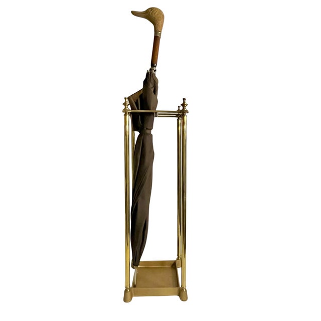 A refined vintage brass umbrella stand featuring a sleek, architectural silhouette with elegant finial details and a warm...