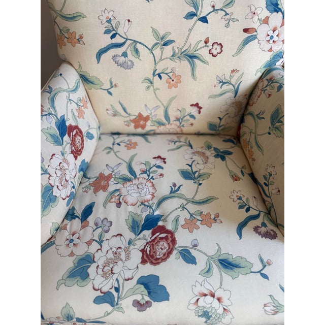 A charming petite vintage accent chair upholstered in a cream-ground chintz-style floral print featuring blue, rust, and...