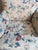 A charming petite vintage accent chair upholstered in a cream-ground chintz-style floral print featuring blue, rust, and...