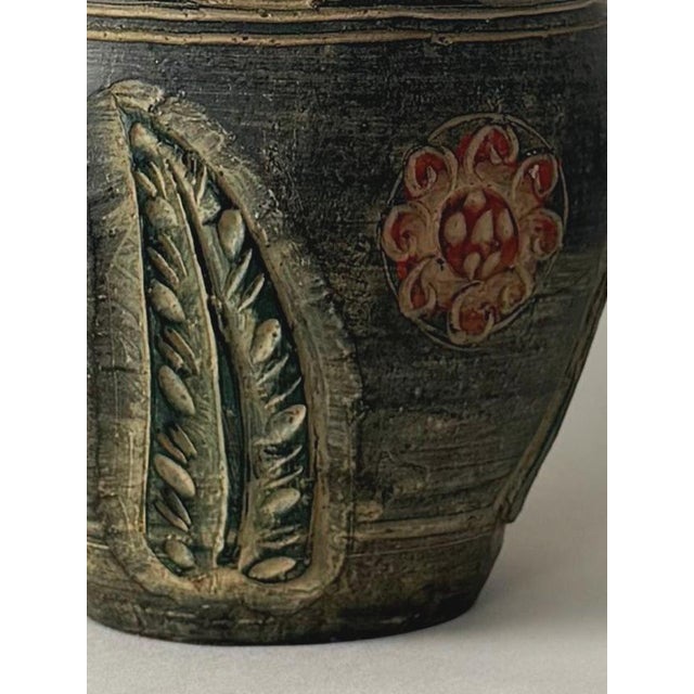 Hand-painted stoneware or ceramic storage vessel with original lid. Dark charcoal base accented with rust-burgundy, cream,...