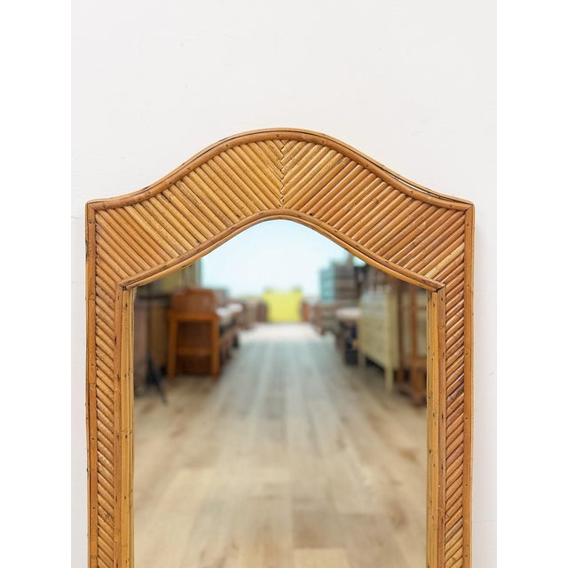 This tall rectangular arched wall mirror features a pencil reed frame, showcasing the fine, tightly woven detailing that...