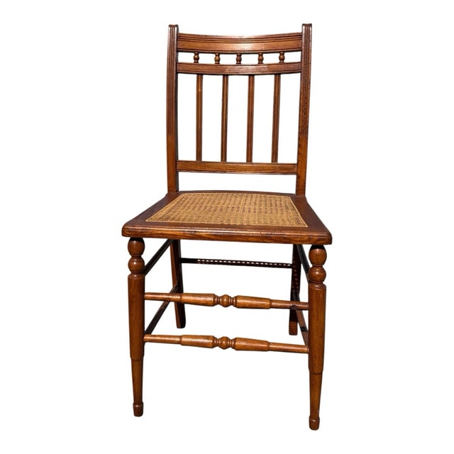 Antique early 20th-century American chestnut side chair featuring a beautifully hand-caned seat, spindle back, and turned...