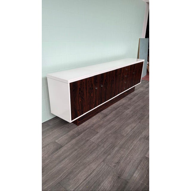German-made sideboard made in the 1970s. White painted frame and Santos rosewood veneer doors. This long sideboard rests...