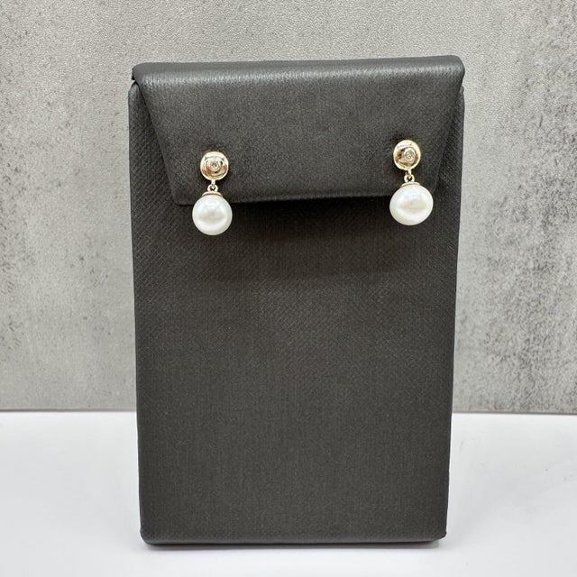 These pearl and diamond dangle earrings are crafted in 10kt yellow gold and feature two 6.5mm round pearls suspended below...