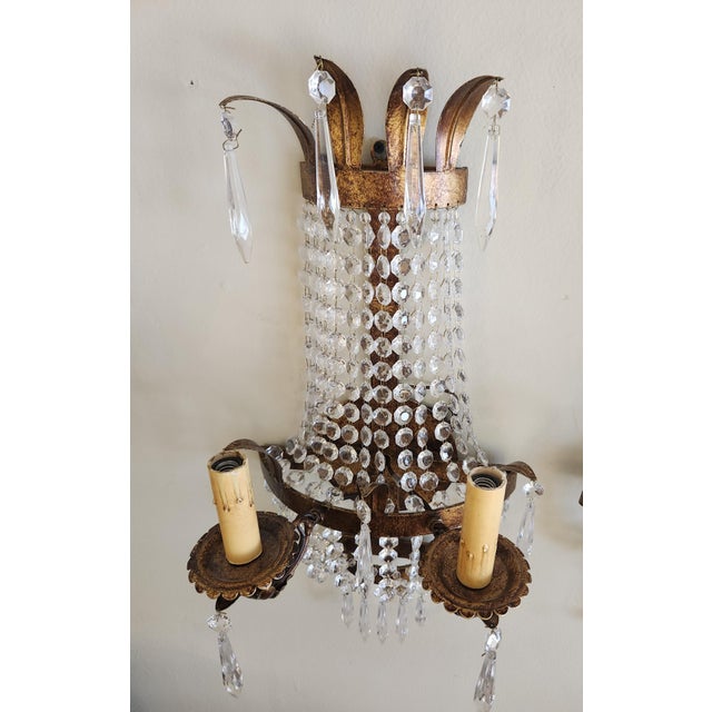 Empire style wall light with crystal prisms. The design features a antique gold leaf over a metal frame along with...