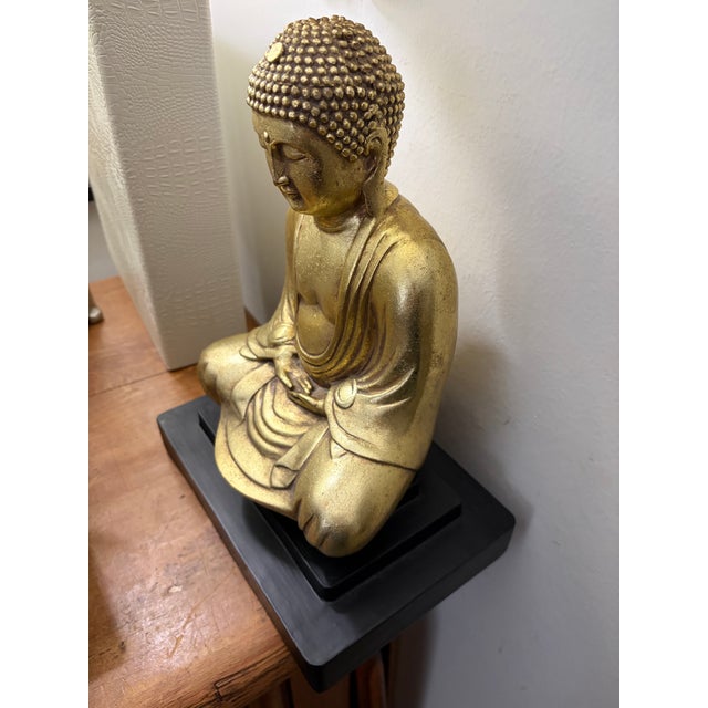 Gold tone ceramic Buda statue in a sitting position on a black wood base Table top decor or shelf filler or covered garden...