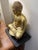 Gold tone ceramic Buda statue in a sitting position on a black wood base Table top decor or shelf filler or covered garden...