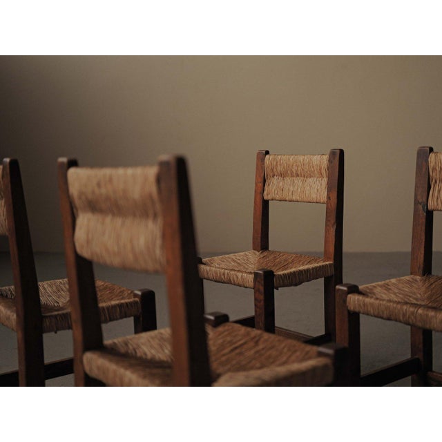 set of four chairs, crafted in France around 1960, features a strong geometric structure in solid oak. The square-section...