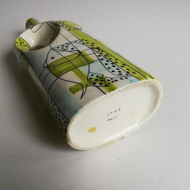 This ceramic bottle shaped vase features abstract drawings and fish decorations. it is colored yellow and black. The vase...
