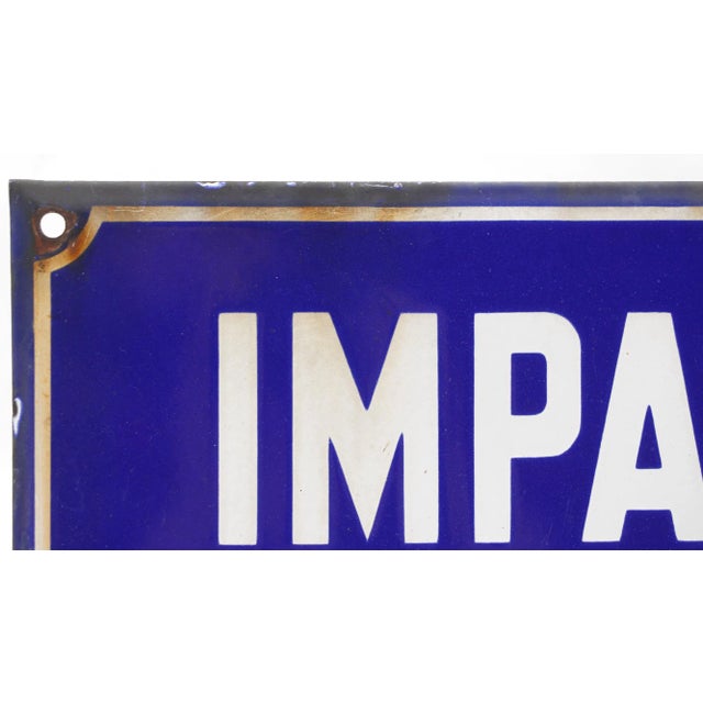 This sign reads, "Impasse Des Lilas" in French, which translates to English, "Dead End of the Lilacs". This rectangular...