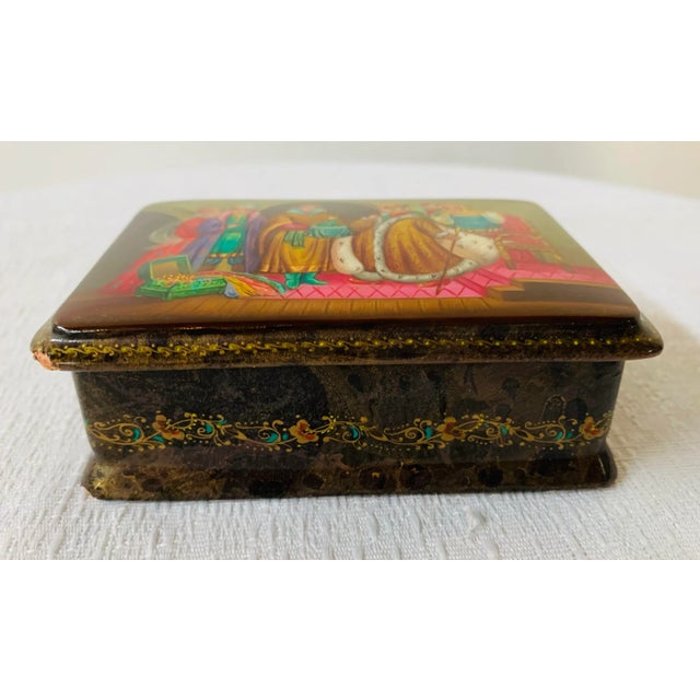A lovely Russian hand-painted lacquered small wooden box with a red interior. The box features the frog princess and...