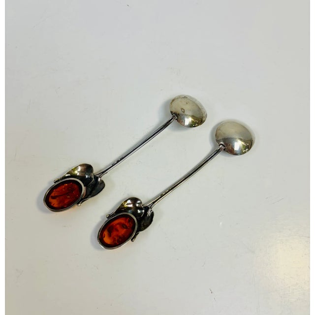 A pair of charming honey/jam/sugar spoons in sterling silver with ovals of Baltic Amber surrounded by leaves and buds at...