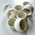 A refined set of eight sculptural napkin rings crafted in matte white painted wood, featuring a softly rounded,...