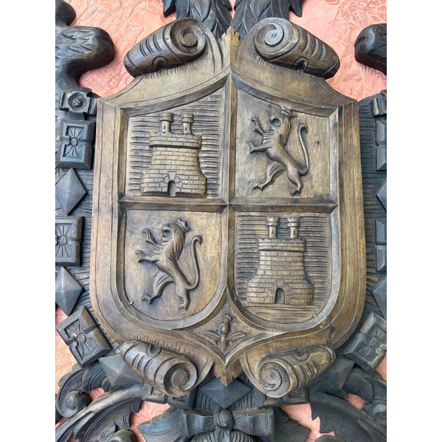 A large and ornately-carved wooden Hapsburg Coat of Arms with a crowned double-headed eagle at the top over a shield with...