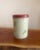 Charming vintage tin canister featuring a delicate floral motif on a soft cream background, topped with a classic red lid....