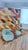 A vivid Boujaad patchwork on a cream ground — thick diagonal bands of orange, mustard, teal, forest green, navy, pink and...