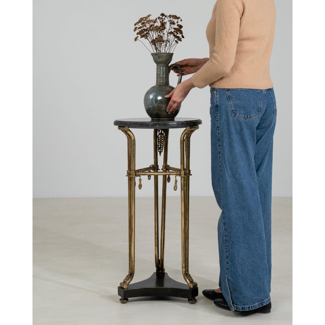 This table makes its impression through gold gilt, black marble base, tripod. Dating to 20th Century and originating from...
