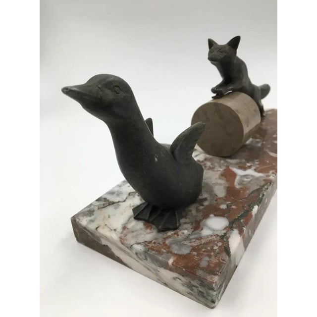 An adorable early Art Deco figure of a fox chasing a duck whilst jumping over a hay barrel. Spelter on red veined marble.